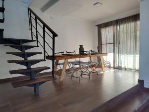 a living room with a table and a wooden staircase at Hornero House in San Antonio de Areco