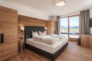 ein Schlafzimmer mit einem großen Bett und einem großen Fenster in der Unterkunft Hubertus Logis Apartments in Brixen im Thale