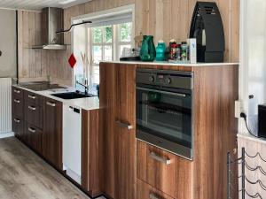 une cuisine avec des armoires en bois et un four à l'intérieur dans l'établissement 4 person holiday home in Hanstholm-By Traum, à Hanstholm