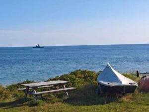 une table de pique-nique et un bateau au bord de l'océan dans l'établissement 16 person holiday home in Glesborg, à Fjellerup Strand 53 autres photos