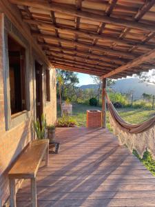 un portico in legno con una panca e un'amaca di Chalé Mirante da Serra a Sabará