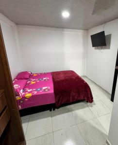 ein Schlafzimmer mit einem Bett mit einer lila Decke in der Unterkunft Bulevar Santa Rosa, apartamento nuevo y acogedor in Santa Rosa de Cabal