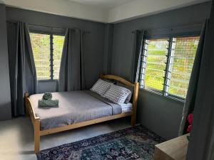 a small bedroom with a bed and two windows at The Athaliah Abode in Suva