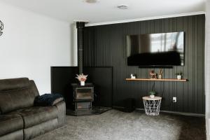 a living room with a couch and a flat screen tv at Marsden Manor - Spacious house with large pool in Greymouth