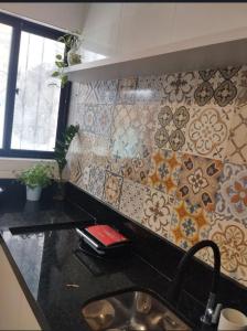 kuchnia ze zlewem i ścianą wyłożoną kafelkami w obiekcie Apê da Rê w mieście João Pessoa +1 zdjęcie