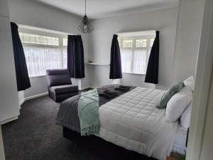 a bedroom with a bed and a chair at Marsden Manor - Spacious house with large pool in Greymouth +20 photos
