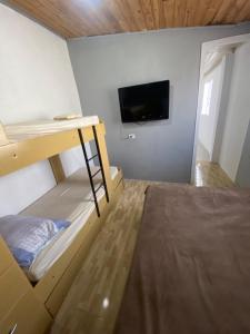 a room with two bunk beds and a flat screen tv at Casa em Coroados - 800 metros da praia in Guaratuba