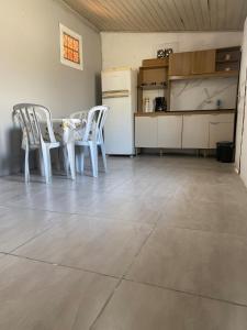 a kitchen with white chairs and a table and a refrigerator at Casa em Coroados - 800 metros da praia in Guaratuba +2 photos