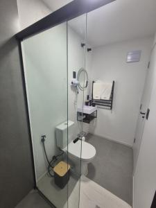 a bathroom with a toilet and a glass shower at Hibisco Guest House in Florianópolis