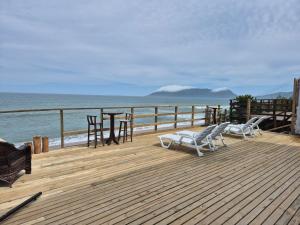 a wooden deck with two chairs and a table on the beach at Hibisco Guest House in Florianópolis +9 photos
