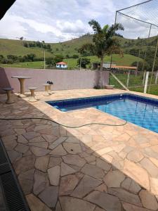 a swimming pool with a stone walkway next to anergynergynergyploadpload at Chalé da Vovó Neusa in Socorro