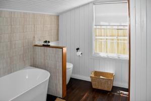 a bathroom with a tub and a toilet and a window at Cedar Cottage Daylesford in Daylesford +54 photos