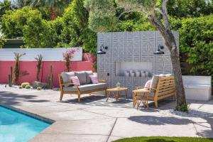 a patio with two chairs and a table next to a pool at The Muse Hotel in Palm Springs