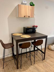 a black table with two chairs and a microwave at Studio cosy, proche Bordeaux et fleuve in Lormont +1 photo