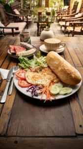 Duck hostel في Vũ Lâm: طبق يحتوي على شطيرة وخضراوات على طاولة خشبية