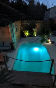 - une piscine bleue dans une cour la nuit dans l'établissement Mas L'Escale des Dentelles, à Aubignan