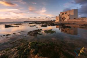 een gebouw aan de kust van een strand met het water bij SUD12 - Case Vacanze sul Mediterraneo in Mazara del Vallo