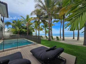 Un patio con sofá y piscina y palmeras. en Elegant Villa, en Los Destiladeros