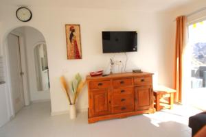 a living room with a wooden dresser and a tv on the wall at Sonja Apartman in Mogán