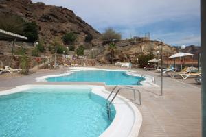 a large swimming pool with a mountain in the background at Sonja Apartman in Mogán