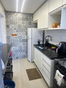 een keuken met witte kasten en een koelkast bij Apatapamento 2 quartos com excelente localização, segurança e com tudo o que você e sua família precisam pra uma estadia confortável! in Feira de Santana
