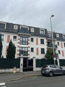 ein Auto, das vor einem großen weißen Gebäude parkt in der Unterkunft Le Cosy 4 de Disney Land paris in Noisy-le-Grand