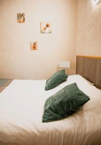 a bed with green pillows on top of it at Hôtel La Batisse in Crémieu