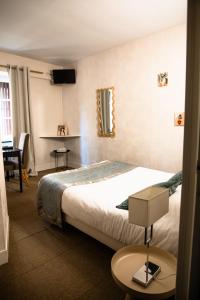 a hotel room with a bed and a table and a television at Hôtel La Batisse in Crémieu +38 photos