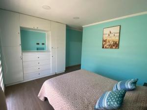 a bedroom with blue walls and a bed and a dresser at Casa Pichilemu in Pichilemu