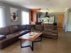 a living room with a brown leather couch and a table at Casa Pichilemu in Pichilemu