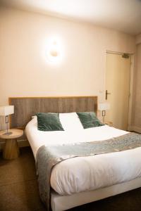 a bedroom with a large bed and two tables at Hôtel La Batisse in Crémieu