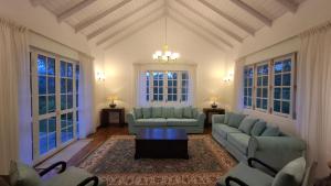 a living room with couches and a table and windows at LilyRose Bungalow at Willows, Upcot, Sri Lanka 