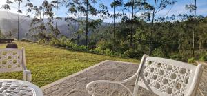 two white chairs sitting on a porch with a view at LilyRose Bungalow at Willows, Upcot, Sri Lanka 