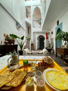 einen Tisch mit Essen darauf im Wohnzimmer in der Unterkunft Riad Dar Malwan Hotel and Massage in Marrakesch