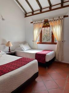 a bedroom with two beds and a window at Cabañas Villa Encanto in Villa de Leyva