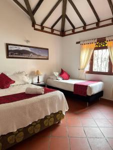 a bedroom with two beds and two windows at Cabañas Villa Encanto in Villa de Leyva