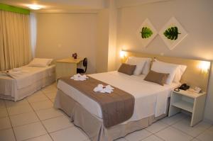 a hotel room with two beds with flowers on them at Marsallis Praia Hotel in Natal