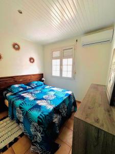 ein Schlafzimmer mit einem Bett mit blauen Laken und einem Fenster in der Unterkunft Villa Krysleen in Le Diamant + 8 Fotos