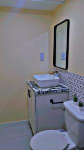 a bathroom with a sink and a toilet with a mirror at Affordable and convenient in town in Saint Georgeʼs
