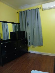 a living room with a television and a dresser with a mirror at ToniqueluxeGuesthouse in Montego Bay