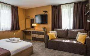 um quarto de hotel com um sofá e uma televisão em Guest House Intrigue em Cherven