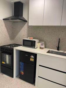 a kitchen with a microwave and a stove and a sink at 2 Bedroom Cozy Space Near Botany in Auckland