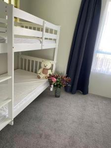 a white bunk bed with a teddy bear and flowers at 2 Bedroom Cozy Space Near Botany in Auckland