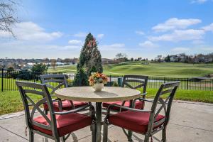 ein Tisch mit vier Stühlen und einer Vase mit Blumen in der Unterkunft Mulligan Manor Golf Course Views Fun Amenities in Green Meadows
