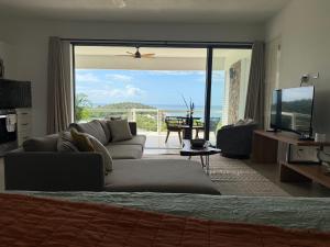a living room with a couch and a large sliding glass door at Pelican at Galley Bay View in Five Islands Village +9 photos