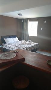 a bedroom with a bed and a table and a window at Aconchego Valença loft in Nova Friburgo