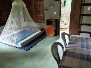 ein Bett mit Moskitonetz in einem Zimmer mit einem Tisch in der Unterkunft Recanto BantuArte-Boipeba in Cayru