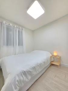 a white bedroom with a bed and a night stand at Haven 10 HOUSE in Seoul