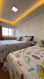 ein Schlafzimmer mit zwei Betten mit einer Steppdecke darauf in der Unterkunft Apê pé na areia com vista mar e próximo ao Beto Carrero - Condomínio Vila Açoriana in Barra Velha + 36 Fotos