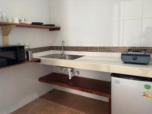 a kitchen with a sink and a microwave at Mae Haad Sunset 2 in Koh Tao